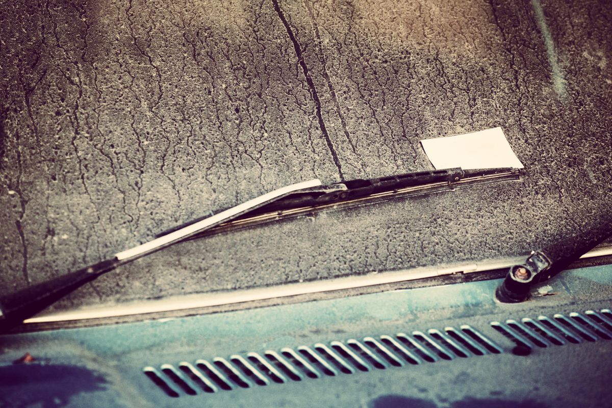 Zettel hinter dem Scheibenwischer eines Autos nach einem selbst verursachten Parkschaden